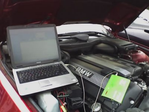 laptop computer hooked up to the engine of a BMW doing a diagnostic test