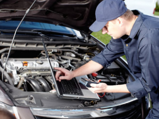 mobile mechanic using his laptop computer to diagnose a cars engine