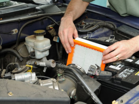 mobile mechanic installing a new air filter in a car during a routine maintenance check