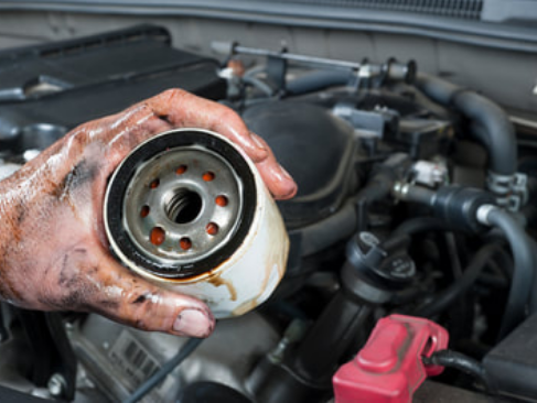 mobile mechanic holding dirty oil filter before installing the new one during a mobile oil change