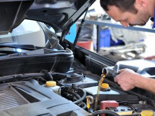 mobile mechanic pouring oil into car after doing a mobile oil change