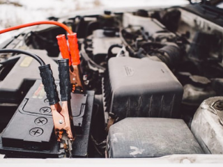 jumper cables hooked up to the battery of a car the will not start due to a dead battery